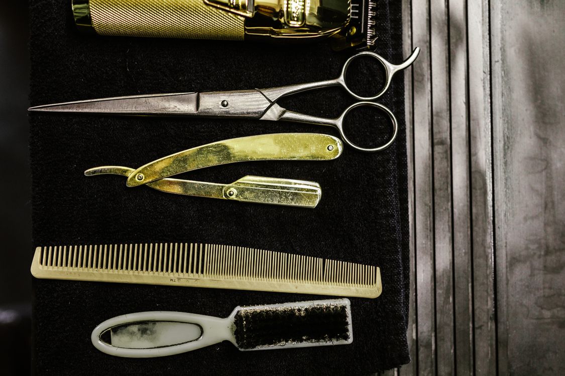 Barber clippers, shears, straight razor and comb laid out on the station